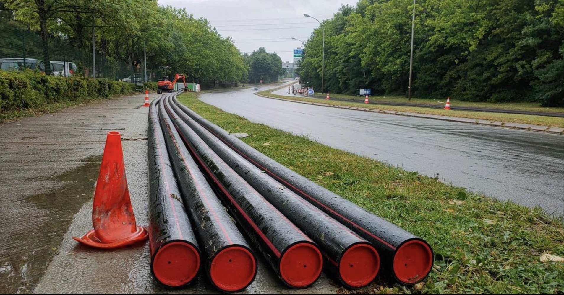 Canalisations PEHD noires à bouchons rouges le long d'une route mouillée