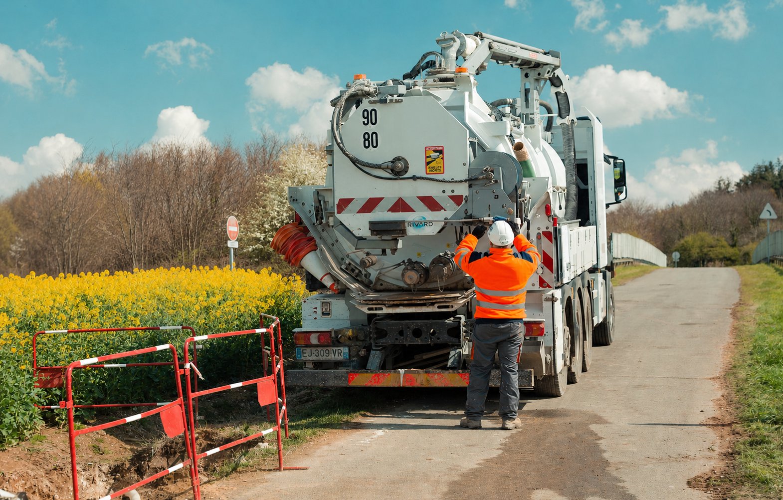 Camion hydrocureur blanc 90/80 au bord d'un champ de colza