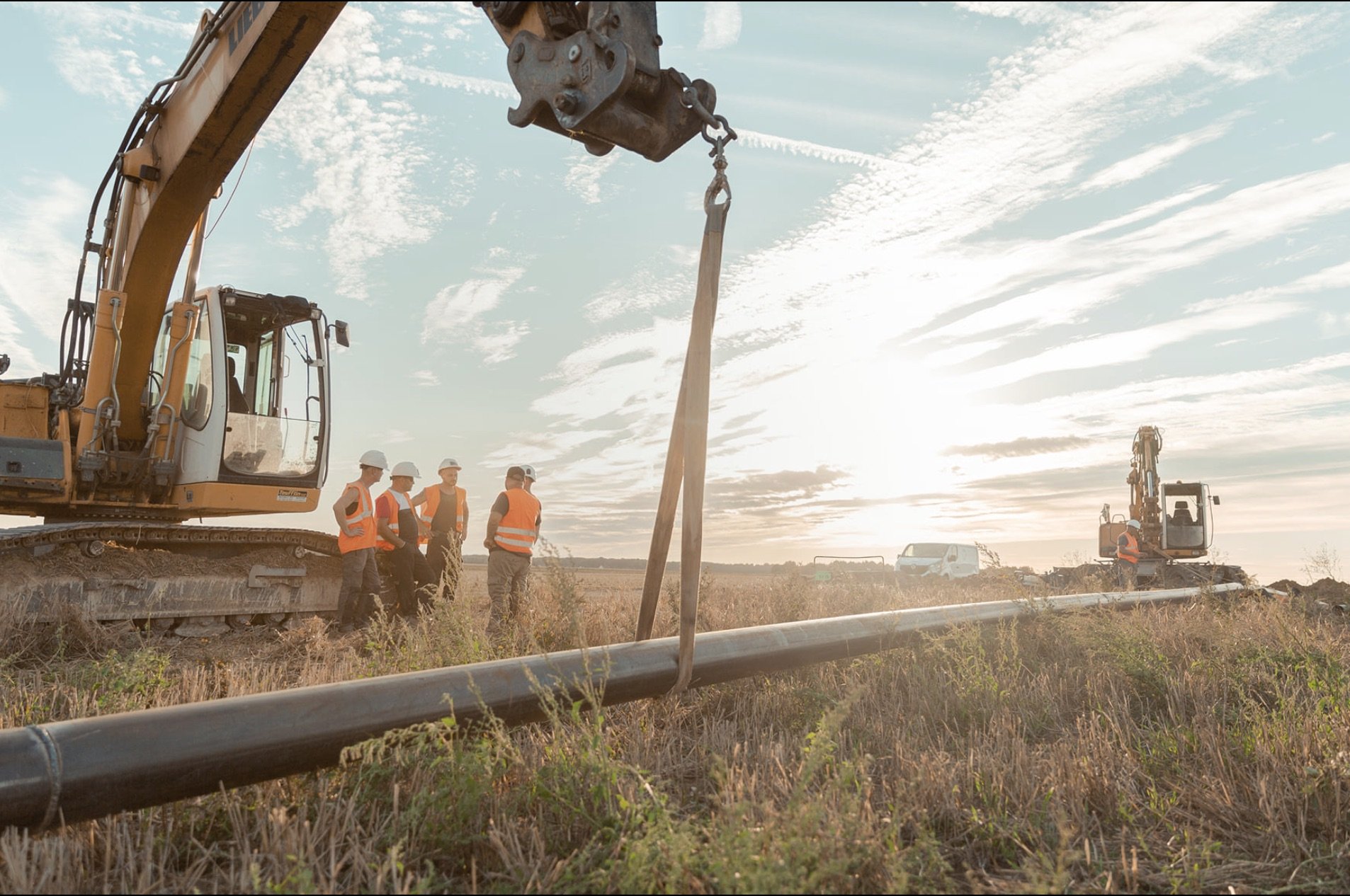 Équipe STPA Forage au coucher de soleil, tirage de canalisation dans un champ